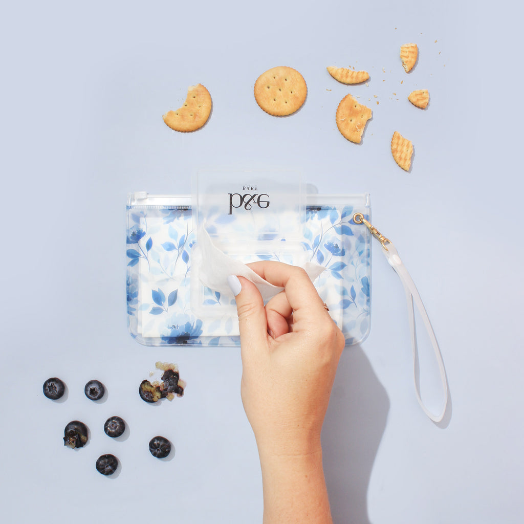 Woman Reaching For A Wipe From A "Sienna" Wipes Case With Blue Floral Design | Ben & Ellie Baby