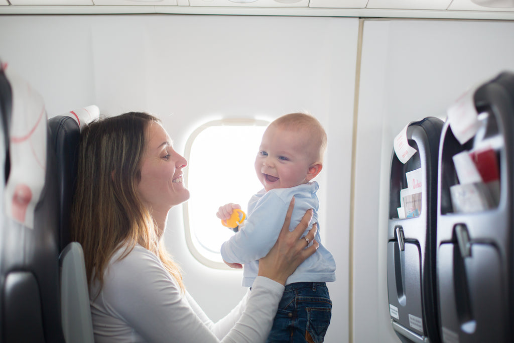 Mother travelling on a plane with a child. 7 ways to make flying with a baby easier, from a frequent flyer mum.