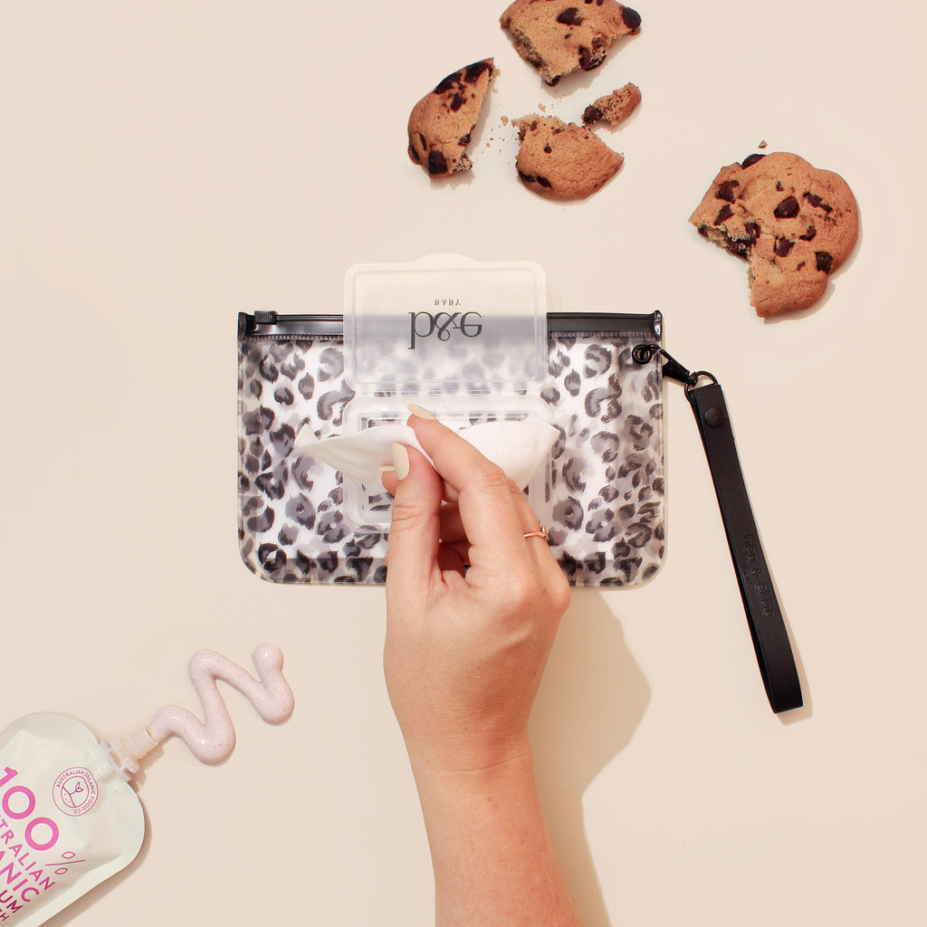 Woman Reaching For A Wipe From A "Sasha" Wipes Case With Leopard Print Design | Ben & Ellie Baby